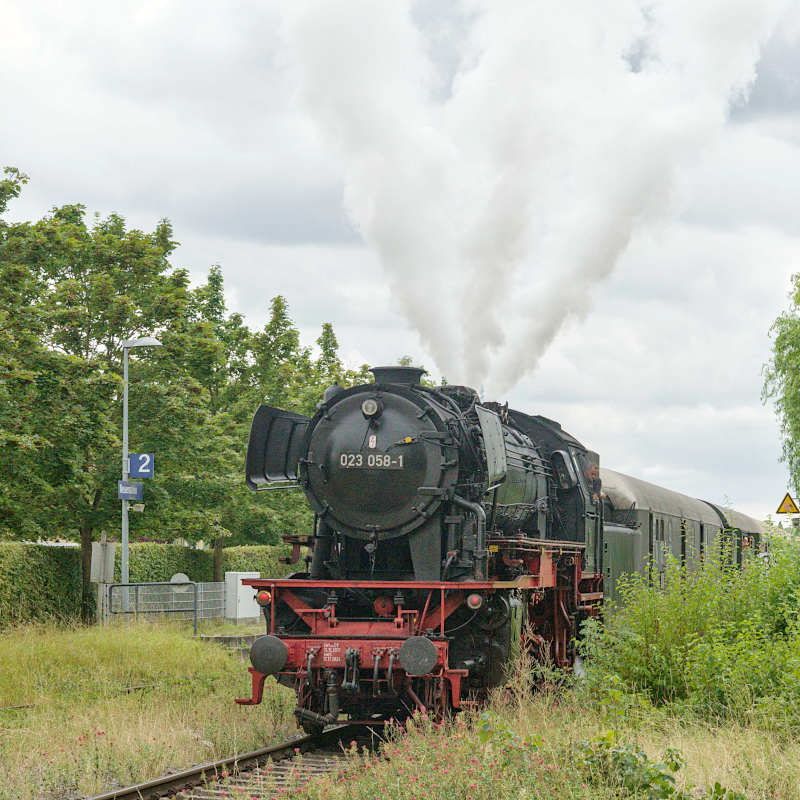 Eine Dampflokomotive an einem Bahnsteig, die Dampf ausstößt